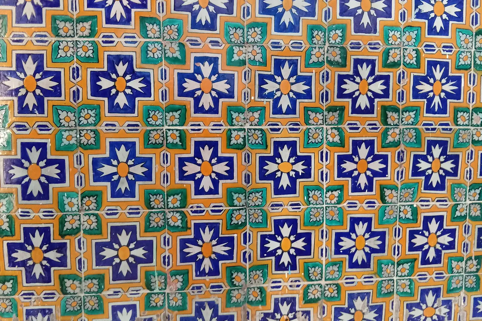 Close-up of glazed ceramic tiles with a repeating blue, green and yellow pattern