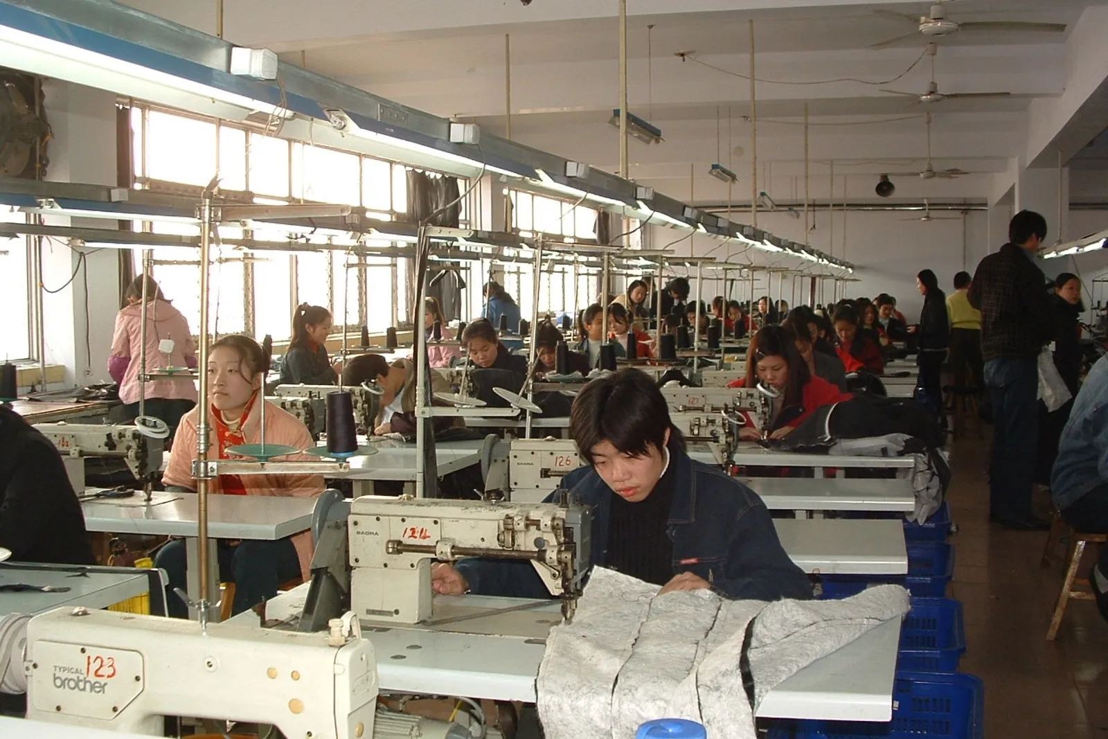 Garment factory sewing floor with rows of operators at industrial sewing machines